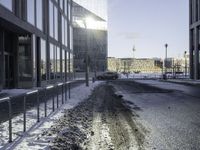 a car parked in the middle of the road near large buildings with snow on them