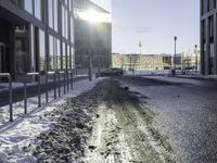 a car parked in the middle of the road near large buildings with snow on them