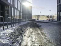 a car parked in the middle of the road near large buildings with snow on them