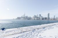 the water and snow are near a pier on the waterfront near a large cityscape