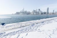 the water and snow are near a pier on the waterfront near a large cityscape