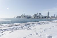 the water and snow are near a pier on the waterfront near a large cityscape