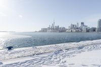 the water and snow are near a pier on the waterfront near a large cityscape