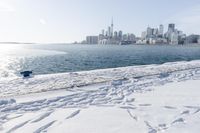 the water and snow are near a pier on the waterfront near a large cityscape