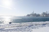 the water and snow are near a pier on the waterfront near a large cityscape