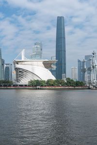 a big building that is in the water near some buildings and skyscrapers above it