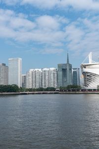 a big building that is in the water near some buildings and skyscrapers above it