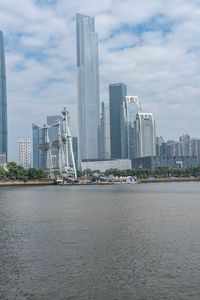 a big building that is in the water near some buildings and skyscrapers above it