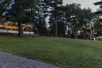 the wedding reception is set on a grassy field with trees surrounding it and lights hanging in the sky