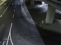 a street with lights and vehicles passing underneath it at night under an elevated expressway at a residential area