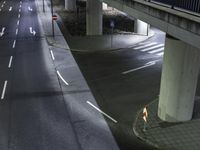 a street with lights and vehicles passing underneath it at night under an elevated expressway at a residential area