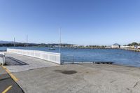 the boardwalk is leading towards the water to a pier next to some boats on the beach