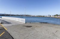 the boardwalk is leading towards the water to a pier next to some boats on the beach