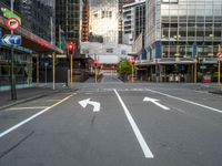 two arrows on a street with buildings in the background, and an empty street that is marked red, at one point