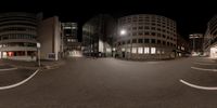 an empty street with some buildings and people in it at night time at the intersection