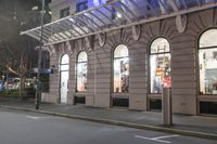 the corner of an empty building has windows lit with brightly lit lights on it's side