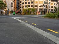 the view from the intersection on a city street with buildings and trees behind it,