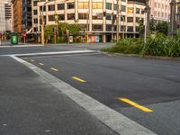 the view from the intersection on a city street with buildings and trees behind it,