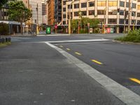 the view from the intersection on a city street with buildings and trees behind it,