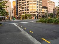 the view from the intersection on a city street with buildings and trees behind it,