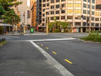 the view from the intersection on a city street with buildings and trees behind it,