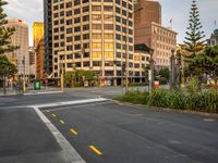 the view from the intersection on a city street with buildings and trees behind it,