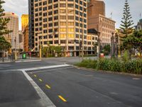 the view from the intersection on a city street with buildings and trees behind it,