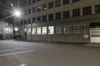 an empty parking lot at night with the sun on top of a building in the background