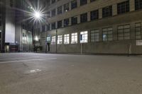 an empty parking lot at night with the sun on top of a building in the background