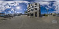 fisheye lens shot showing street with large boat dock and buildings in background with sun