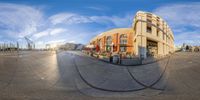 a panorama lens with an old yellow building in the background and the sky filled with clouds