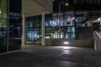 the lights are on at the entrance to a building with many windows and steps in it