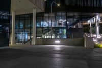 the lights are on at the entrance to a building with many windows and steps in it