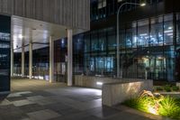 an entrance to a large office building at night with lights shining on the side of the building