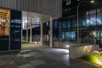 an entrance to a large office building at night with lights shining on the side of the building