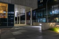 an entrance to a large office building at night with lights shining on the side of the building