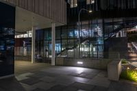 an entrance to a large office building at night with lights shining on the side of the building