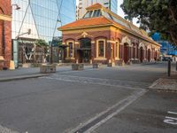 an older fashioned building has a orange roof and a yellow shin roof and pillars at the end of the street