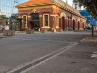 an older fashioned building has a orange roof and a yellow shin roof and pillars at the end of the street