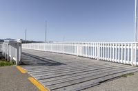 the boardwalk is leading towards the water to a pier next to some boats on the beach