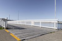 the boardwalk is leading towards the water to a pier next to some boats on the beach