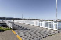 the boardwalk is leading towards the water to a pier next to some boats on the beach