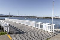 the boardwalk is leading towards the water to a pier next to some boats on the beach