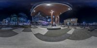 a fish eye view of a public square with people walking around and an illuminated street at night