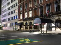 a city street with a few buildings and an umbrella on the corner at night,