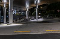 a sidewalk under an overpass at night with stairs and steps up to it in the foreground