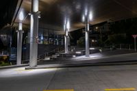 a sidewalk under an overpass at night with stairs and steps up to it in the foreground