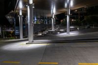 a sidewalk under an overpass at night with stairs and steps up to it in the foreground