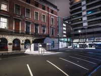 a street at night with a parking lot and building behind it and lights on the windows