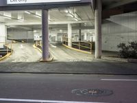 an empty parking garage with two signs on it's sides and a sidewalk area with steps next to it